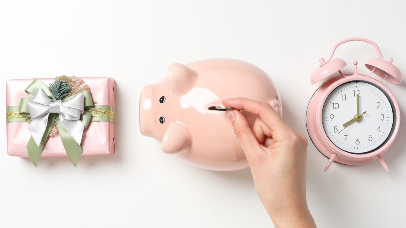 piggy-bank-hand-with-coin-gift-box-clock-white-background-top-view-1-scaled-1
